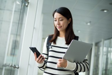 cep telefonu kullaranarak dizüstü bilgisayar ile kız öğrenci