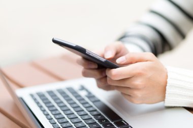Dizüstü bilgisayar ve cep telefonu kullanan kadın