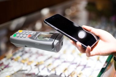 Fatura ödeme için cep telefonu kullanan kadın