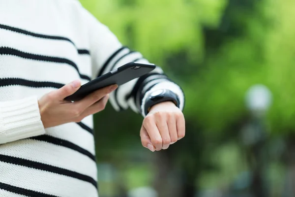 Vrouw mobiele telefoon aansluiten met smart watch — Stockfoto