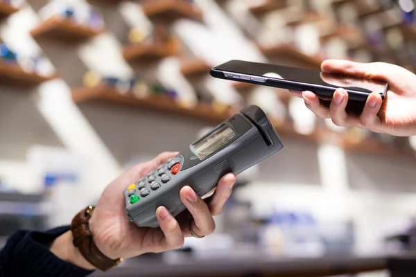 Kvinner som bruker mobiltelefon til å betale regningen – stockfoto