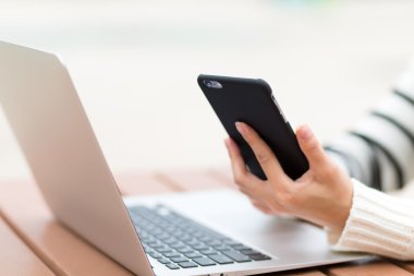 Dizüstü bilgisayar ve cep telefonu kullanan kadın