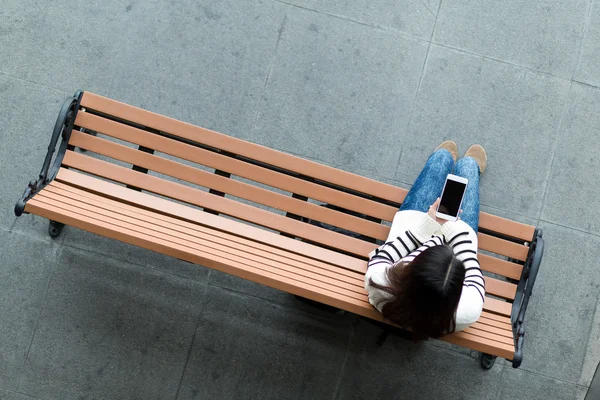 Mujer en el banco usando el teléfono móvil —  Fotos de Stock