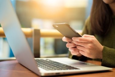 Dizüstü bilgisayar ve cep telefonu kullanan kadın