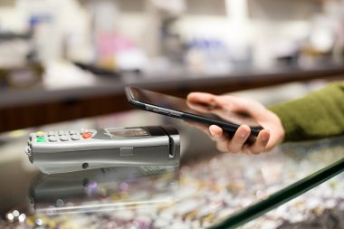 Fatura ödeme için cep telefonu kullanan kadın
