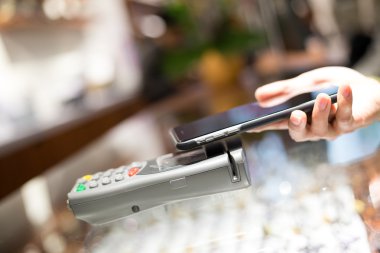 Fatura ödeme için cep telefonu kullanan kadın