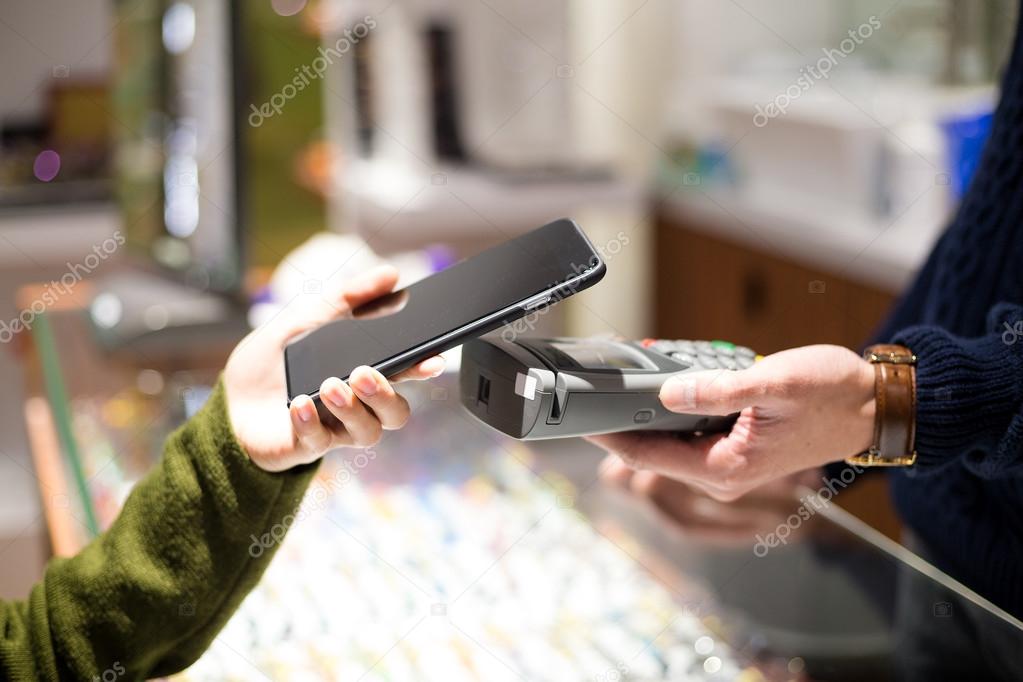 Woman using cellphone for paying the bill