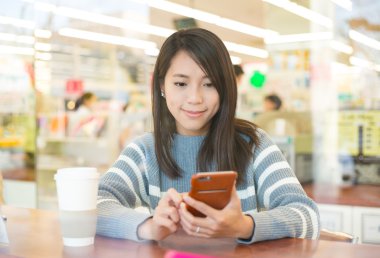 Kahve dükkanında cep telefonu kullanan kadın