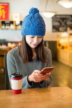 Kahve dükkanında cep telefonu kullanan kadın