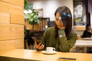 kahve dükkanında akıllı telefon kullanan kadın