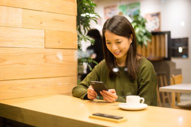 kahve dükkanında akıllı telefon kullanan kadın