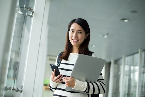 Kvinnlig student med laptop och mobiltelefon — Stockfoto