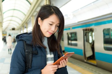 Tren platformu akıllı telefon kullanan kadın
