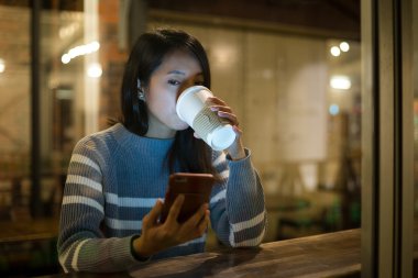 kahve içme ve cep telefonu kullanan kadın