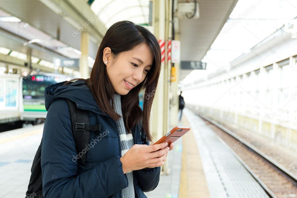 woman using cellphone at train platform