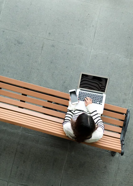 Mujer usando ordenador portátil y teléfono celular —  Fotos de Stock