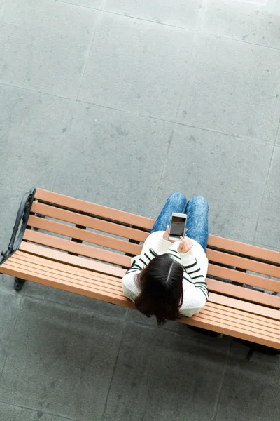在使用移动电话的长椅上的女人 — 图库照片