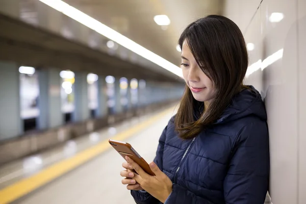 Жінка використовує мобільний телефон на станції метро — стокове фото