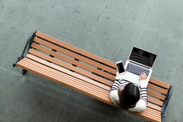 Vrouw met laptopcomputer en mobiele telefoon — Stockfoto