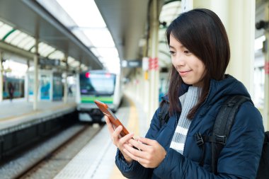 tren istasyonunda cep telefonu kullanan kadın