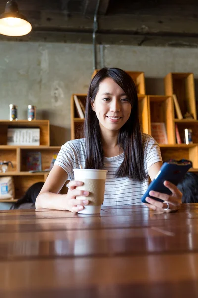 Жінка насолоджується кавою і використовує мобільний телефон — стокове фото