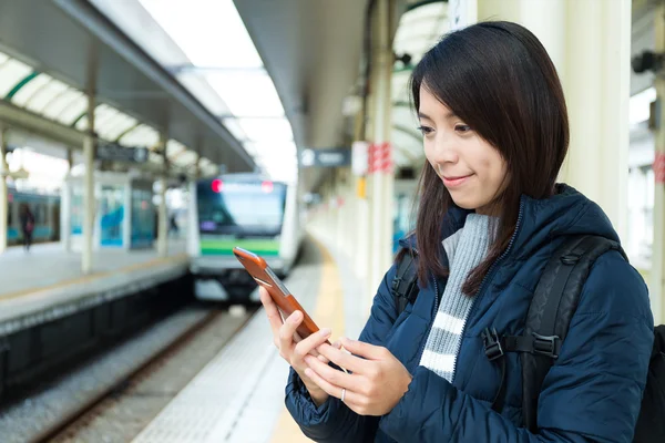 Žena pomocí mobil na vlakovém nádraží — Stock fotografie