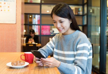 kahve dükkanında cep telefonu kullanan kadın