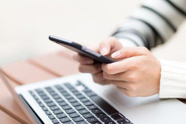 dizüstü bilgisayar ve cep telefonu kullanan kadın