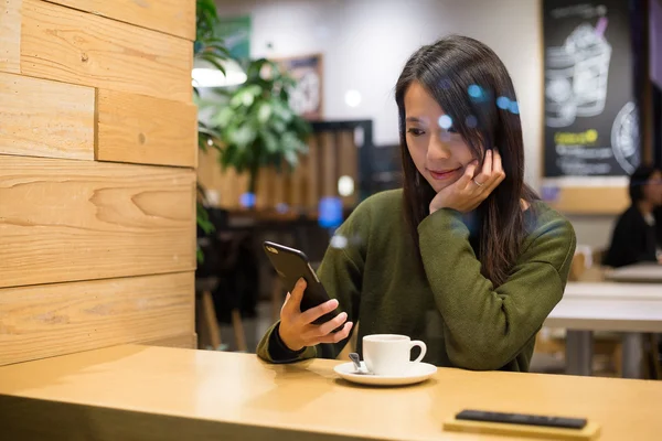 Kafede cep telefonu kullanan kadın