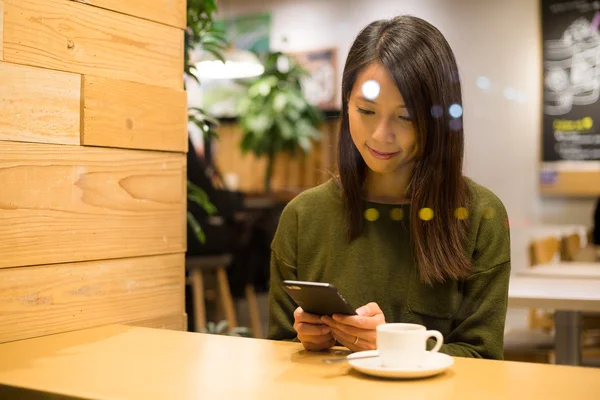 Kafede cep telefonu kullanan kadın