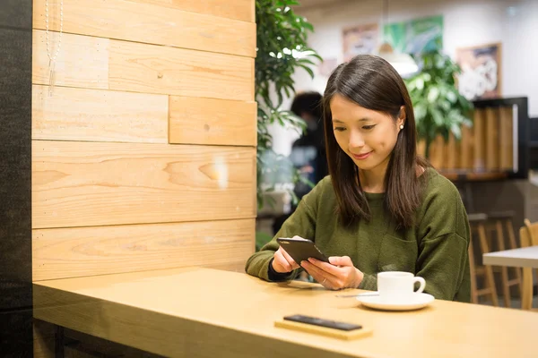 Kafede cep telefonu kullanan kadın