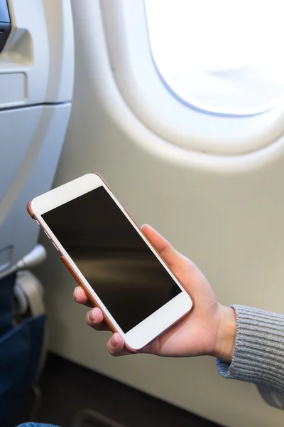 Vrouw met behulp van smartphone in vliegtuig — Stockfoto