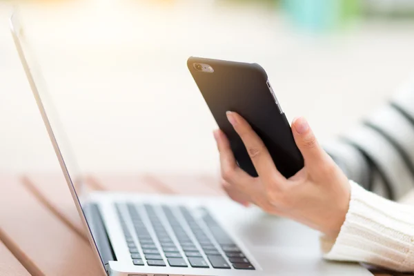 Woman using mobile phone with notebook computer — Stock Photo, Image