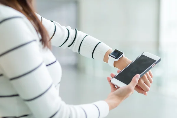 Kvinde forbinder smart ur og mobiltelefon - Stock-foto