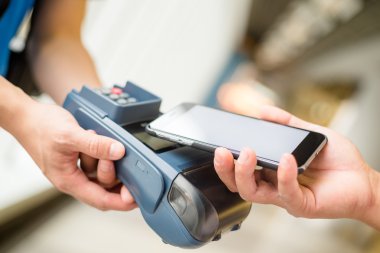 Fatura ödeme için cep telefonu kullanan kadın