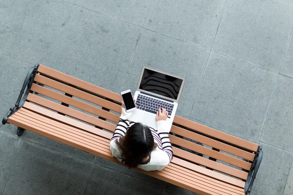 Vrouw met laptopcomputer en mobiele telefoon — Stockfoto