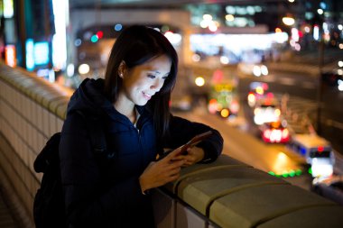 Geceleri cep telefonu kullanan bir kadın.