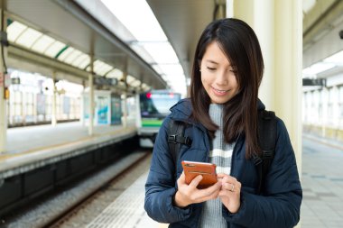 Tren platformu cep telefonu kullanan kadın