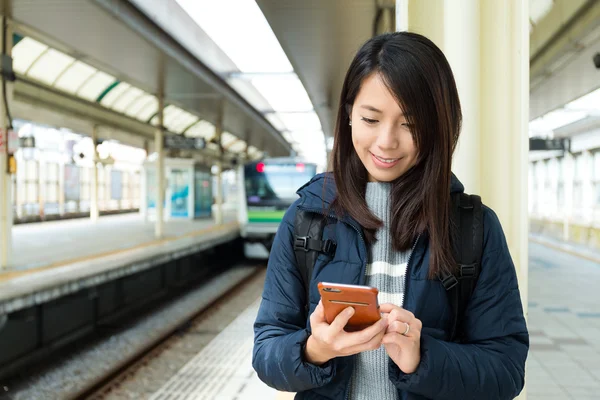 Woman using cellphone at train platform — Stock Photo, Image