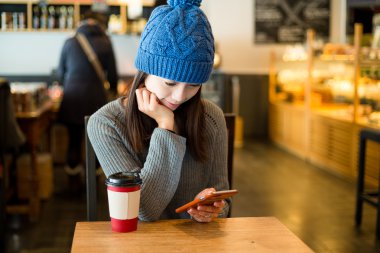 Kahve dükkanında cep telefonu kullanan kadın