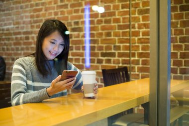 Kahve dükkanında cep telefonu kullanan kadın