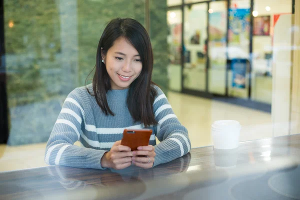 Vrouw met behulp van mobiele telefoon in de coffeeshop — Stockfoto