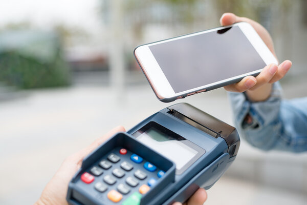 Woman using cellphone for paying the bill