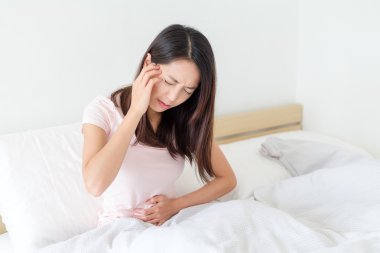 Mide ağrısı ve baş ağrısı olan kadın
