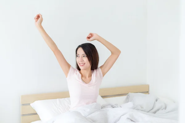Frau streckt sich nach dem Aufwachen im Bett — Stockfoto