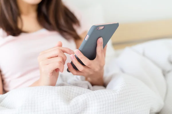 Wanita menggunakan ponsel di tempat tidur — Stok Foto