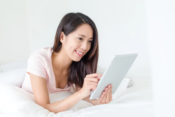 Frau benutzt Tablet-PC und liegt im Bett — Stockfoto