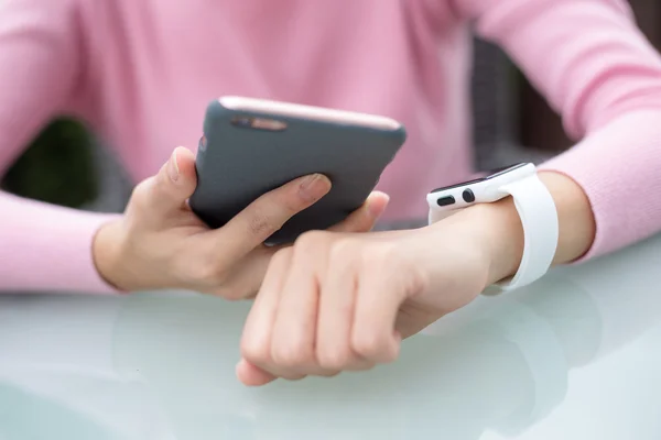 Mujer conectando reloj inteligente y teléfono celular — Foto de Stock