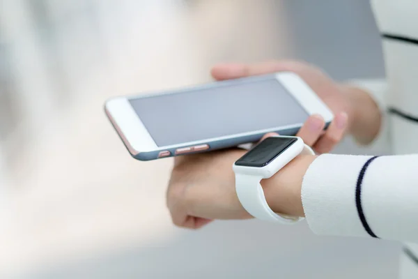 Mujer conectando reloj inteligente y teléfono celular — Foto de Stock