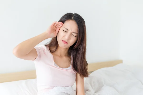 Frau hat Kopfschmerzen und sitzt im Bett — Stockfoto